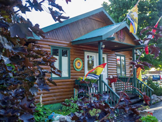 A log cabin with a porch and flags on the front.