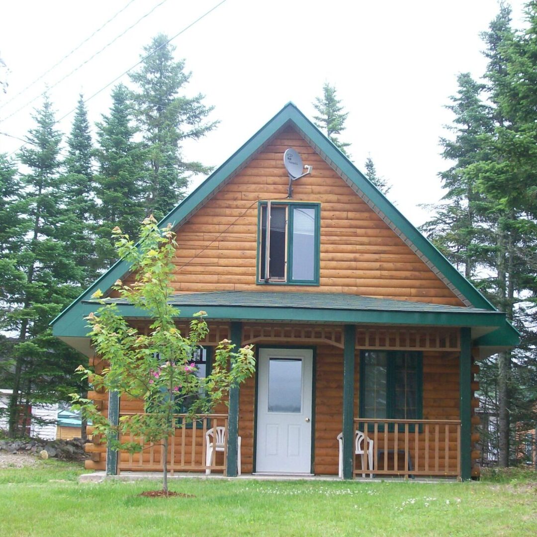 A small cabin with a porch and trees in the background.