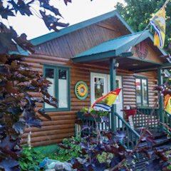 A log cabin with a porch and flags on the front.