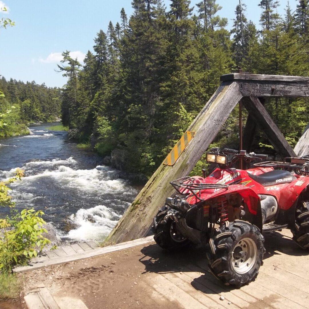 A red atv parked on the side of a bridge.